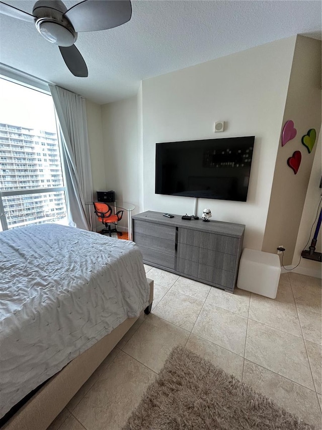 tiled bedroom with ceiling fan and a textured ceiling