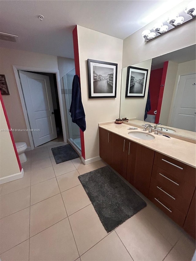 bathroom with toilet, vanity, baseboards, a shower stall, and tile patterned floors