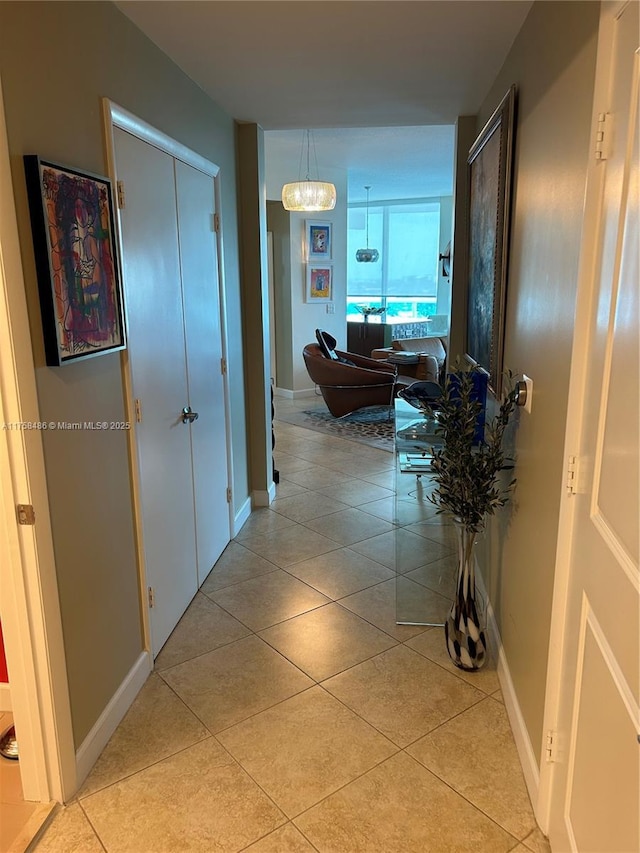 hall featuring light tile patterned flooring and baseboards