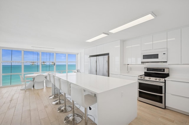 kitchen featuring light wood finished floors, a kitchen bar, white cabinets, stainless steel appliances, and modern cabinets