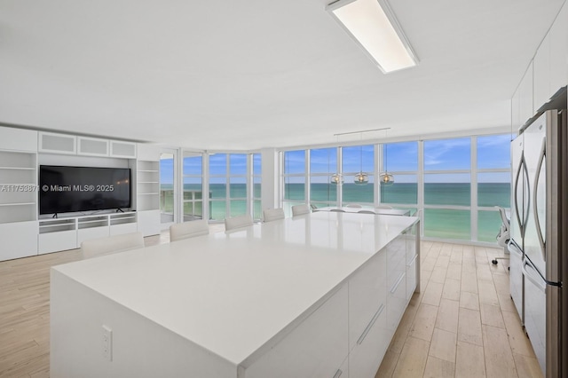 kitchen with light wood-style flooring, freestanding refrigerator, a water view, white cabinetry, and modern cabinets