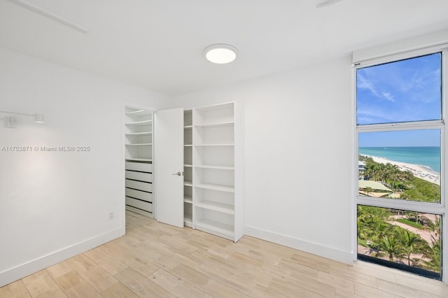 interior space featuring a water view, wood finished floors, and baseboards