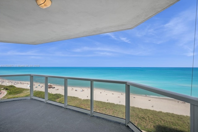 balcony featuring a water view and a beach view