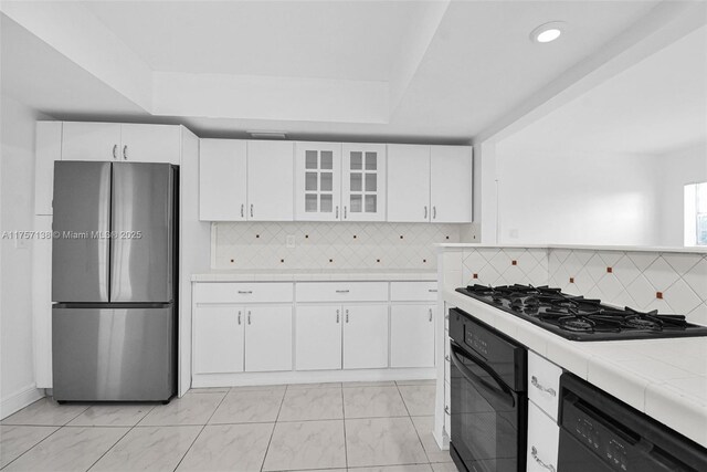 8790 SW 84th St, Miami, FL 33173 - kitchen with tile countertops, white cabinets, black appliances, a tray ceiling, and glass insert cabinets