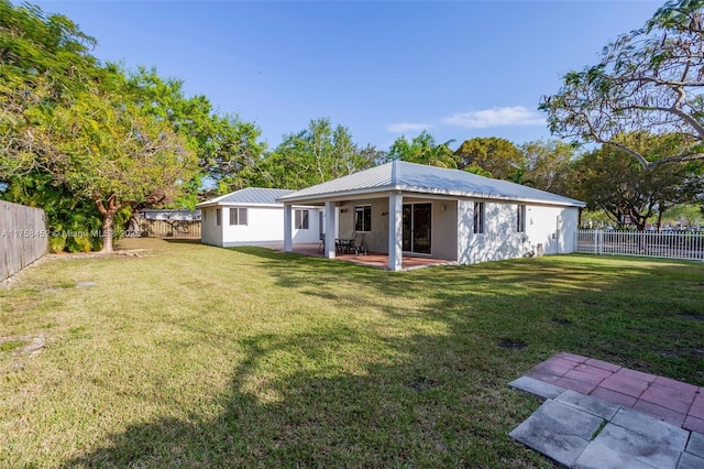 rear view of house with a patio area, a lawn, metal roof, and a fenced backyard