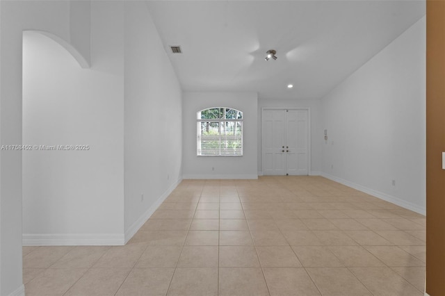 spare room with light tile patterned floors, visible vents, baseboards, recessed lighting, and arched walkways