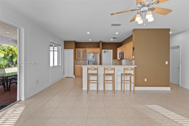 kitchen with visible vents, a peninsula, decorative backsplash, light countertops, and appliances with stainless steel finishes