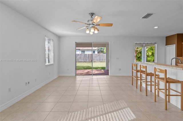 interior space with light tile patterned floors, a healthy amount of sunlight, visible vents, and ceiling fan