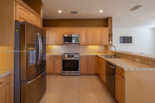 kitchen featuring tile counters, visible vents, stainless steel appliances, and a sink