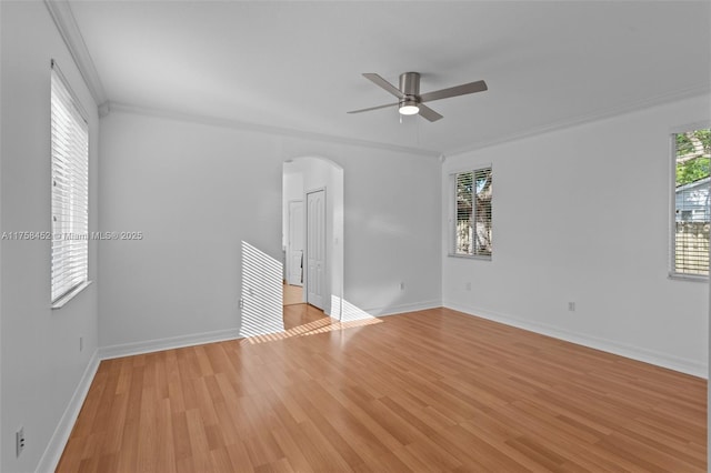 spare room with arched walkways, light wood-style floors, and crown molding