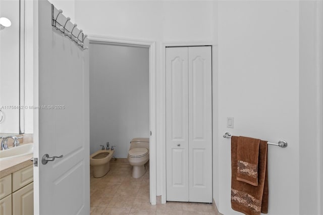 bathroom featuring vanity, a bidet, tile patterned flooring, a closet, and toilet