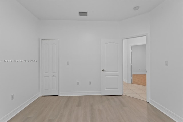 unfurnished room featuring light wood-type flooring, visible vents, and baseboards