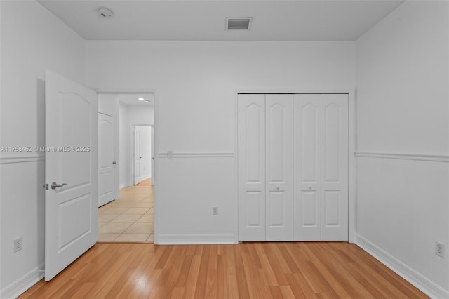 unfurnished bedroom featuring light wood-style floors, visible vents, and baseboards