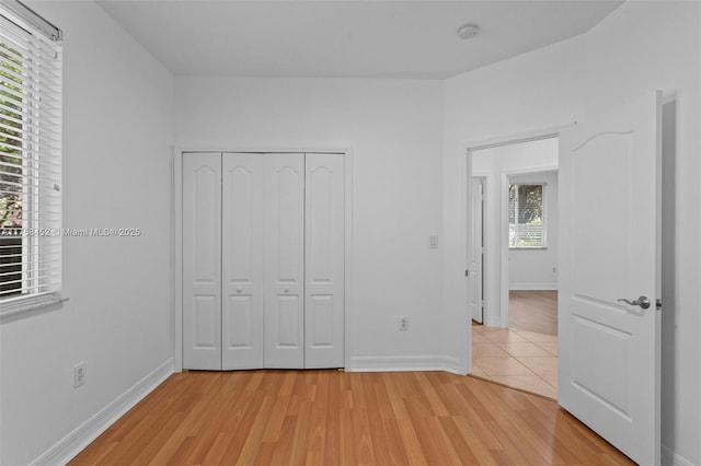 unfurnished bedroom with a closet, baseboards, and light wood-style flooring