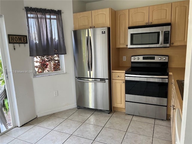 kitchen featuring stainless steel appliances, light tile patterned floors, plenty of natural light, and light brown cabinetry