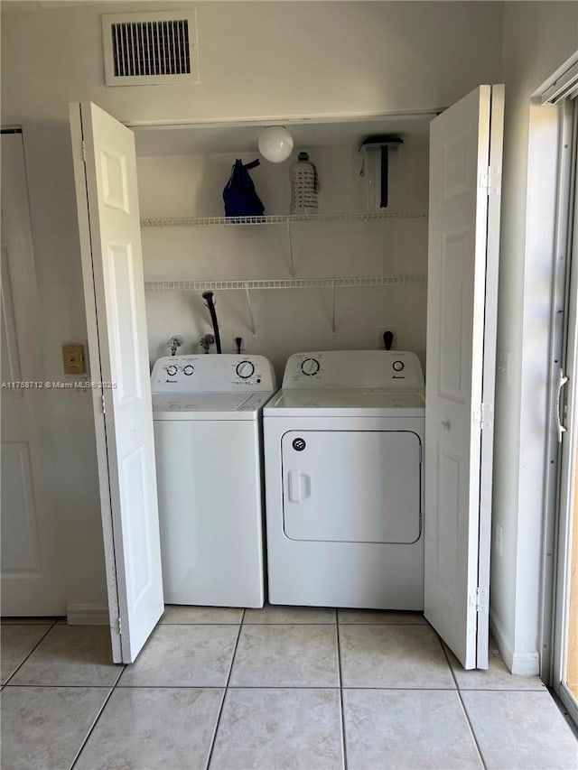 clothes washing area featuring laundry area, washer and clothes dryer, light tile patterned flooring, and visible vents