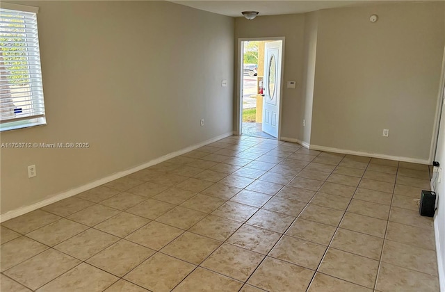 spare room featuring light tile patterned flooring and baseboards