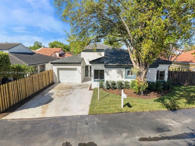 ranch-style house featuring stucco siding, an attached garage, a front yard, fence, and driveway