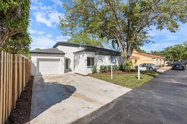 view of front of property featuring stucco siding, concrete driveway, an attached garage, fence, and a front lawn