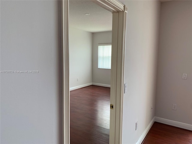 corridor with dark wood-style floors and baseboards