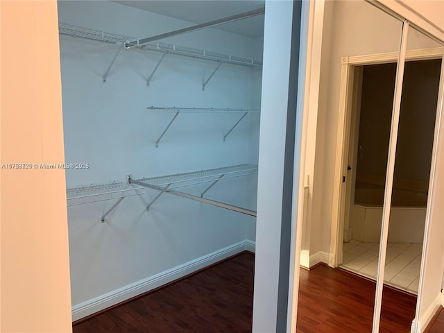 walk in closet with wood finished floors