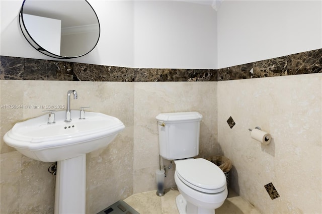 half bath featuring toilet and tile walls