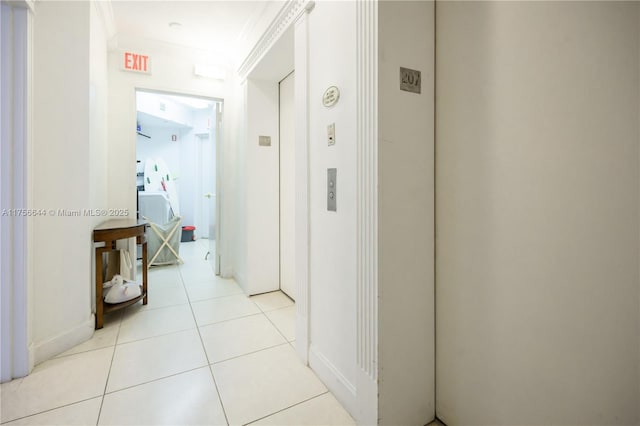 hallway with elevator, light tile patterned flooring, and ornamental molding