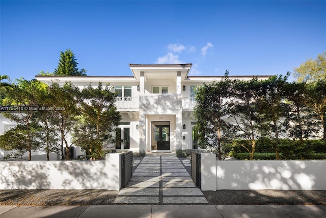 view of front of home featuring a fenced front yard, french doors, stucco siding, a gate, and a balcony