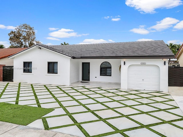 ranch-style house featuring a tile roof, fence, an attached garage, and stucco siding