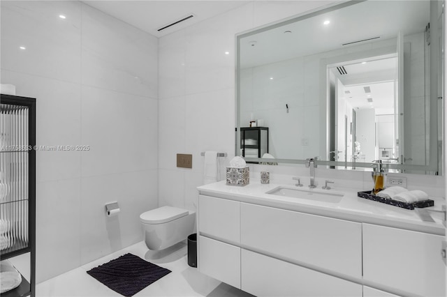 bathroom featuring visible vents, vanity, toilet, and tile walls