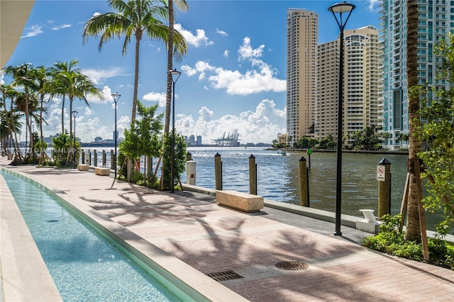 view of swimming pool with a dock, a water view, and a view of city