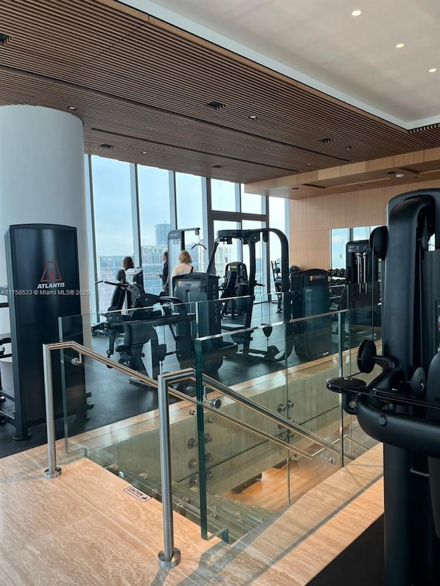 exercise room with a city view, a wall of windows, and wood finished floors