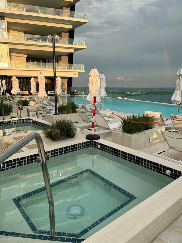 view of swimming pool with a water view and a hot tub