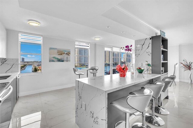 kitchen with light stone counters, marble finish floor, baseboards, and a kitchen breakfast bar