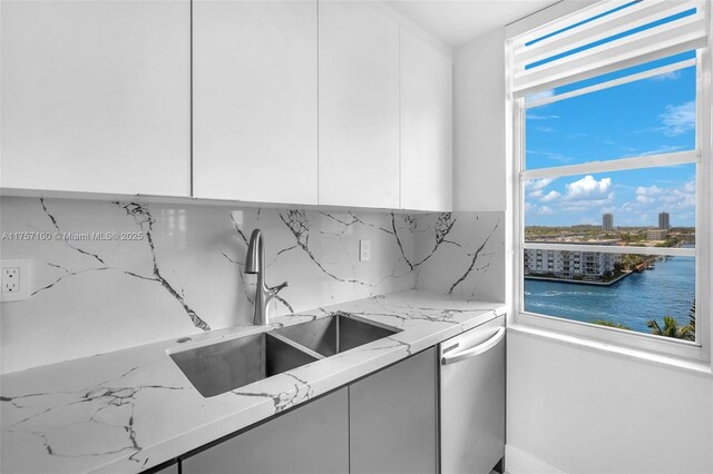 kitchen with light stone counters, a sink, white cabinets, backsplash, and modern cabinets