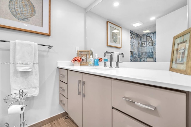 bathroom with recessed lighting, vanity, wood finished floors, baseboards, and walk in shower