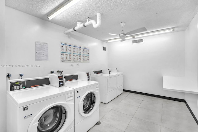 community laundry room featuring a textured ceiling, light tile patterned flooring, visible vents, a ceiling fan, and washer and clothes dryer