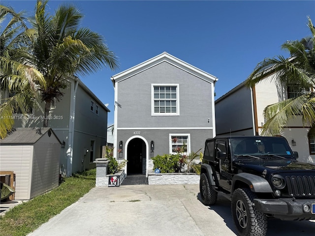 traditional-style house with a storage unit, an outbuilding, and stucco siding