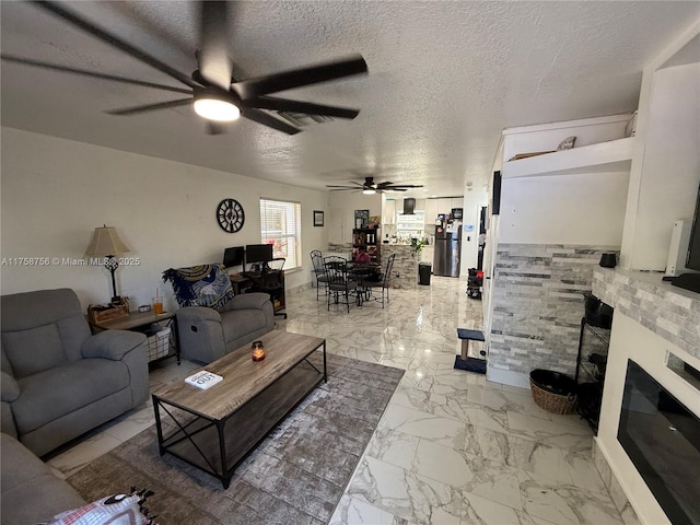 living area featuring marble finish floor, a fireplace, and a textured ceiling