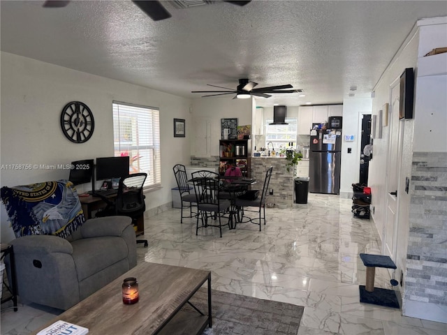 living room featuring a textured ceiling, marble finish floor, and a ceiling fan