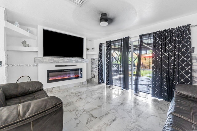 living room with marble finish floor, visible vents, a glass covered fireplace, ceiling fan, and a textured ceiling