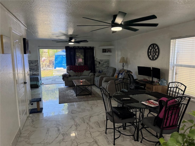 dining area featuring marble finish floor, a ceiling fan, and a textured ceiling