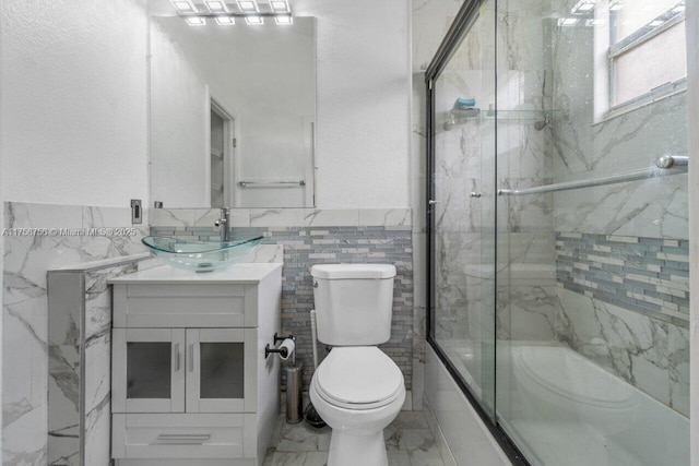 bathroom with vanity, tile walls, a textured wall, toilet, and marble finish floor