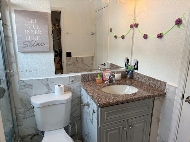 bathroom with toilet, a textured wall, vanity, and tile walls