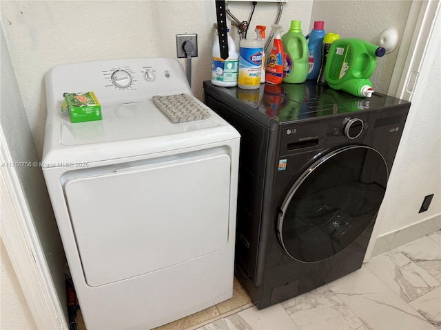 laundry room featuring a textured wall, marble finish floor, separate washer and dryer, and laundry area