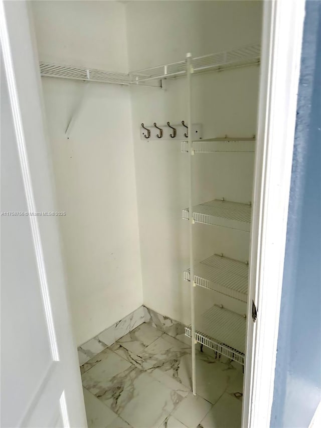 walk in closet with marble finish floor