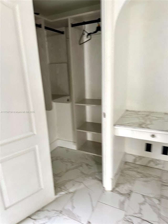 walk in closet with marble finish floor