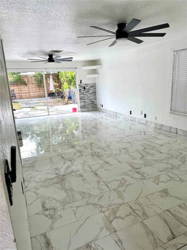 spare room featuring marble finish floor, a textured ceiling, and a ceiling fan