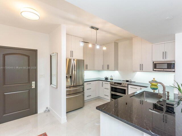 kitchen with stainless steel appliances, a sink, baseboards, dark stone counters, and decorative light fixtures