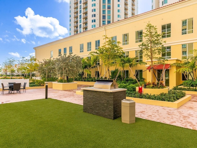 view of community with a patio area, a lawn, and an outdoor kitchen